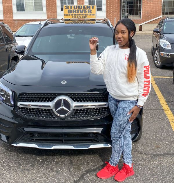 Student holding a key in front of school car